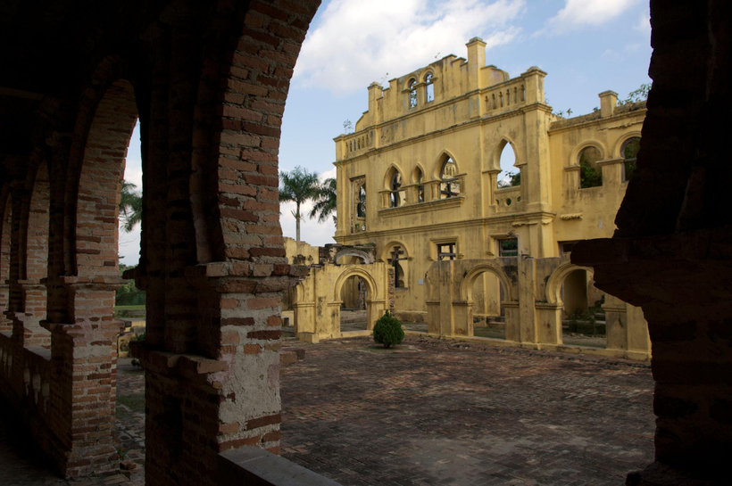 Yellow House seen through a brick courtyard arch